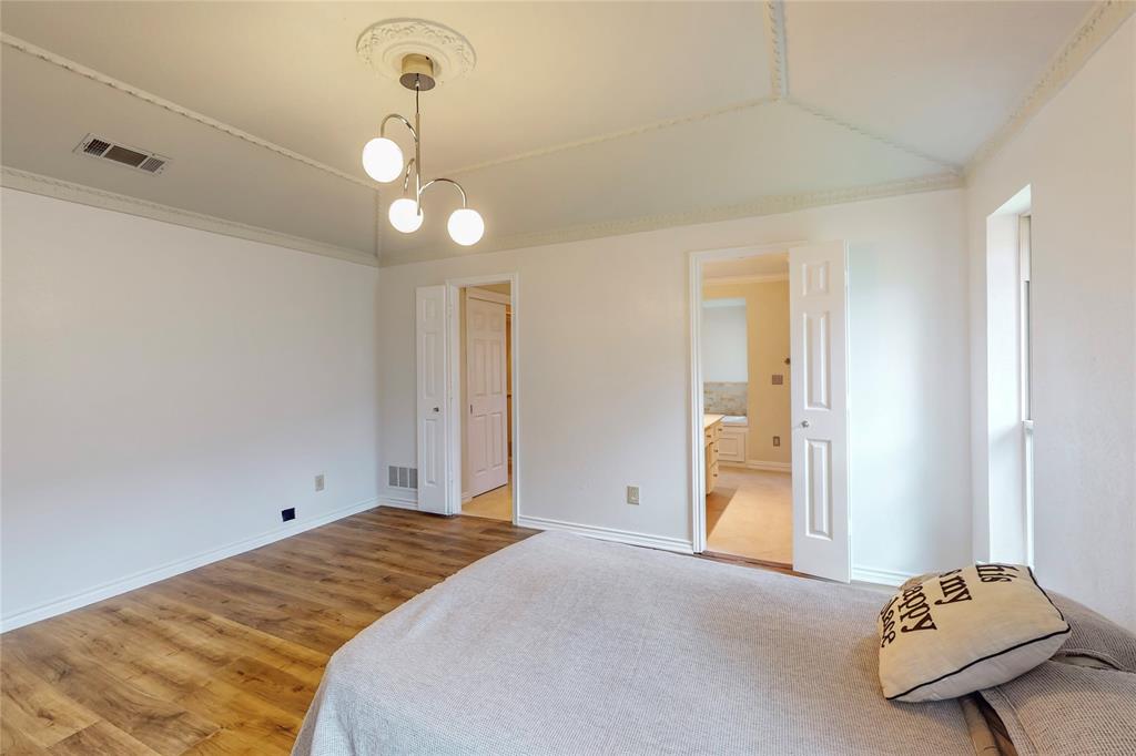 Wood-finish flooring with white baseboards, a vaulted ceiling with crown molding, and a decorative ceiling medallion with a contemporary light fixture