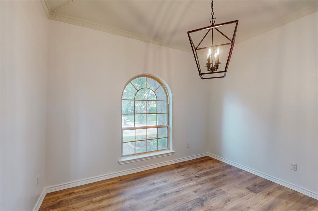Arched window, wood-finish flooring, decorative crown molding, and a four-light geometric chandelier