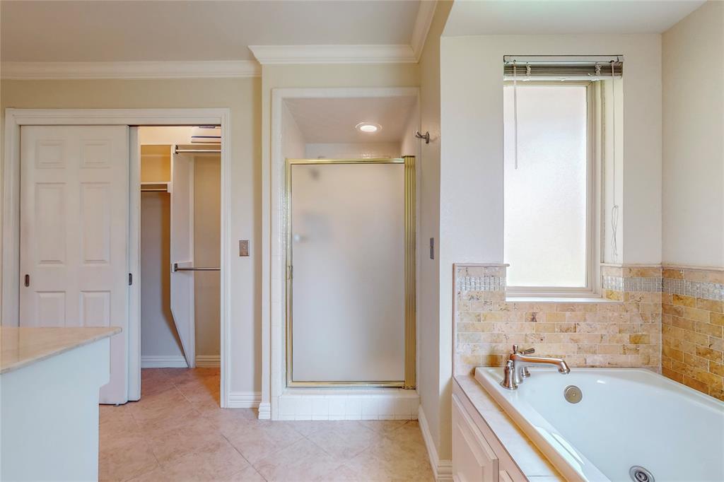 Soaking tub with deck-mounted fixtures, tiled surround with accent detailing, and a separate shower enclosure
