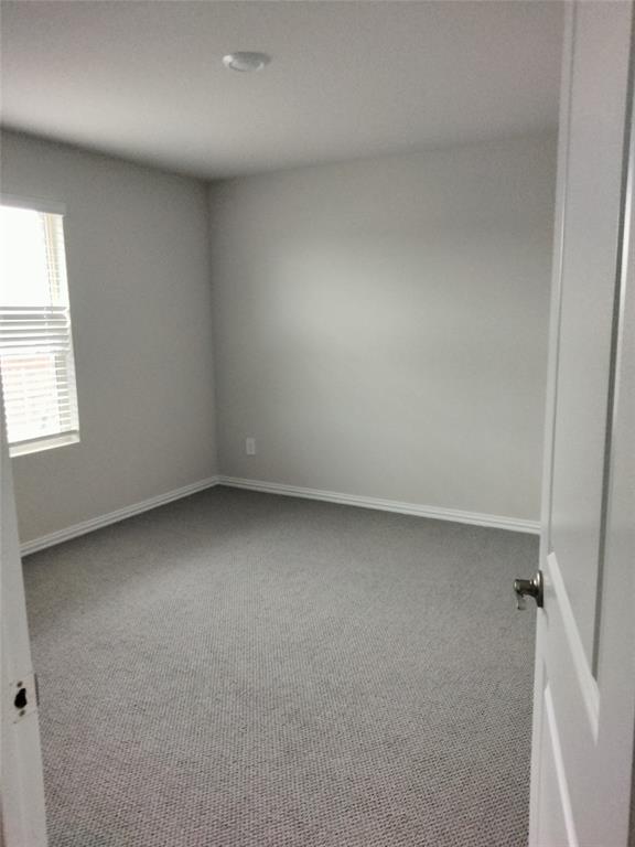 Neutral tone wall paint, grey textured carpet, white trim, recessed ceiling light, and a window with blinds