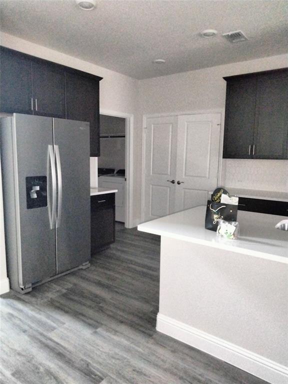 Wood-finish flooring, dark cabinetry, white countertops, recessed lighting, and a double-door entry
