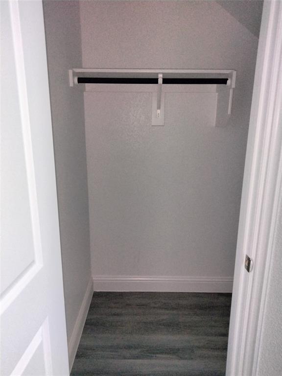 Built-in closet shelving with hanging rod and wood-finish flooring