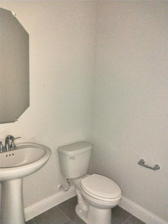 Pedestal sink with chrome-finish faucet, toilet, and gray tile flooring