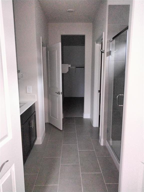 Tile flooring, dark wood-finish vanity, white countertop, glass-enclosed shower, recessed lighting