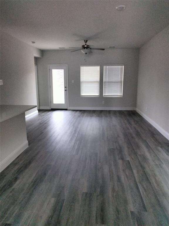 Wood-finish flooring, ceiling fan, white trim, recessed lighting, and multiple windows with blinds