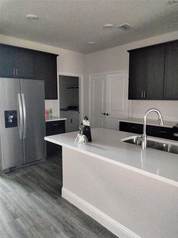 Kitchen featuring a center island, stainless steel refrigerator, dark wood-finish cabinetry, and a stainless steel sink with a high-arc faucet