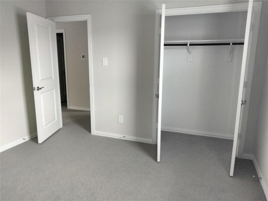 Neutral-toned wall paint, light gray carpet flooring, white paneled doors, and a closet with a hanging rod