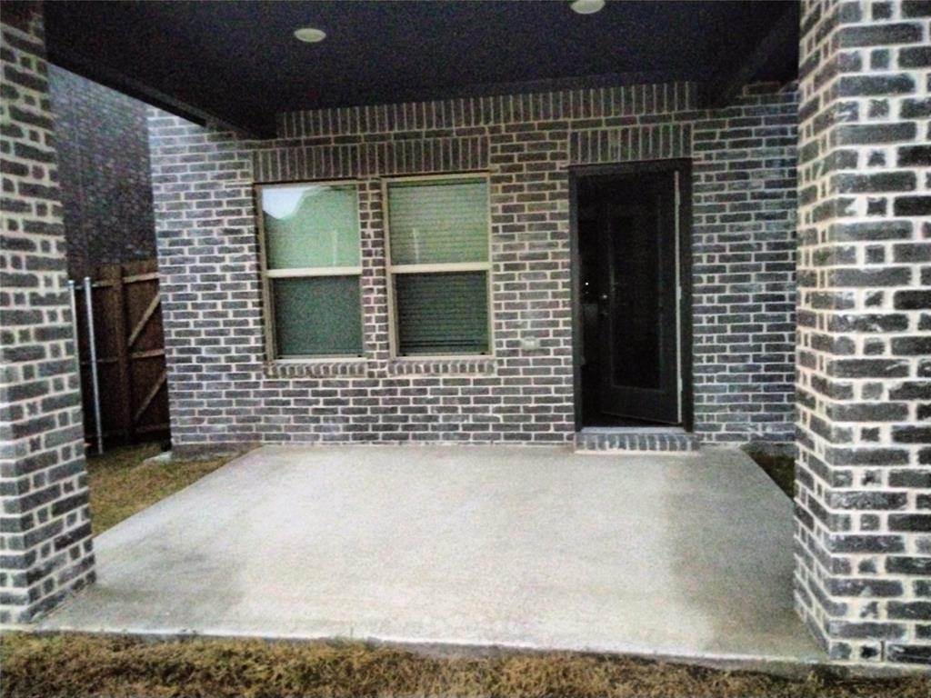Concrete patio featuring a dark brick exterior, recessed lighting, and a dark-framed entry door