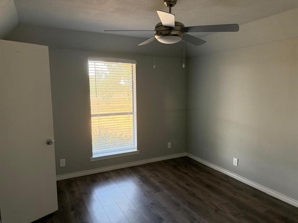 Wood-finish flooring, neutral wall tones, window with horizontal blinds, and a ceiling fan with integrated lighting