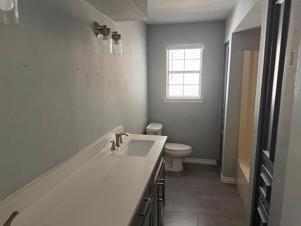 Vanity with integrated sink, brushed nickel faucet, and a window with horizontal blinds