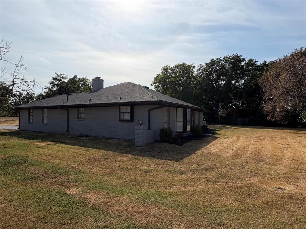Single-story residence with a gray exterior, dark-framed windows, and a dark shingle roof Single-story residence with a gray exterior, dark-framed windows, and a dark shingle roof