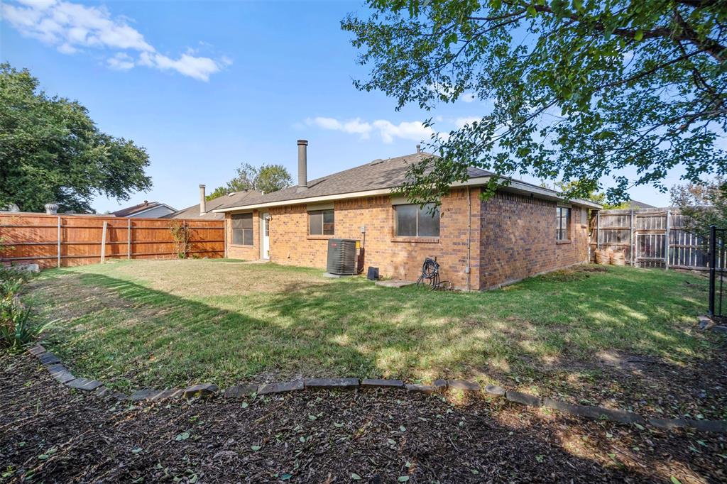 Brick exterior featuring a hip roof, chimney, and wood fencing enclosing the rear grounds
