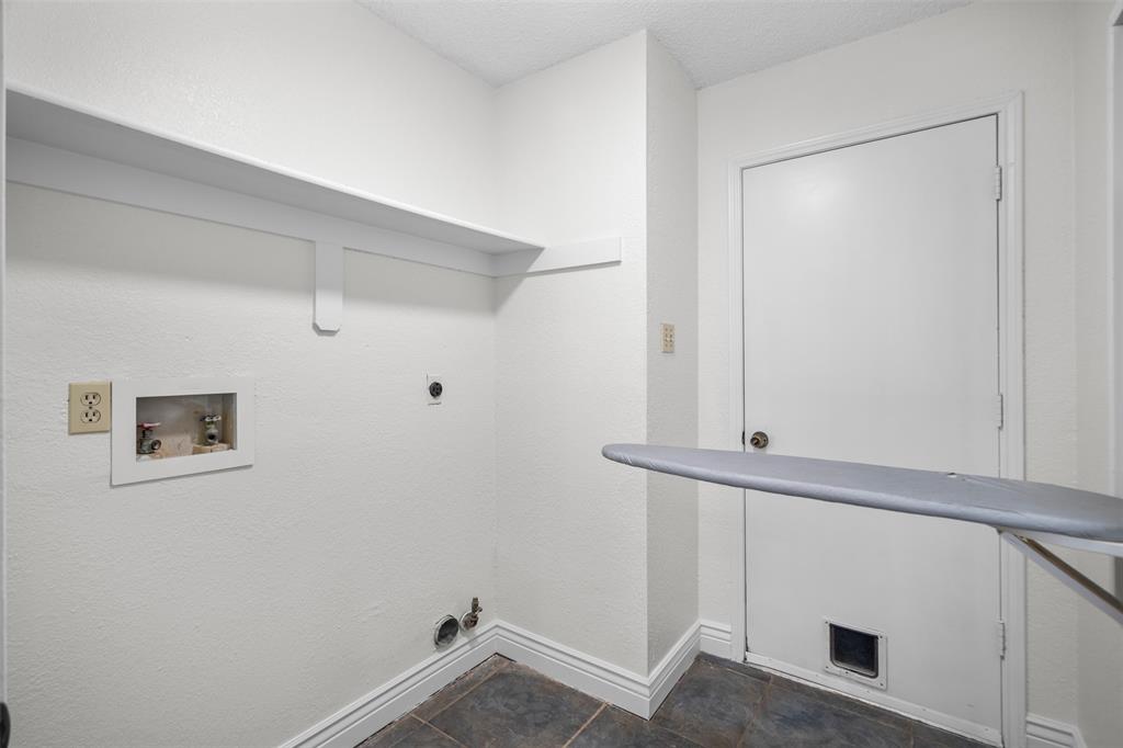 Dedicated laundry area featuring tile flooring, built-in shelving, recessed utility hookups, and a wall-mounted ironing board