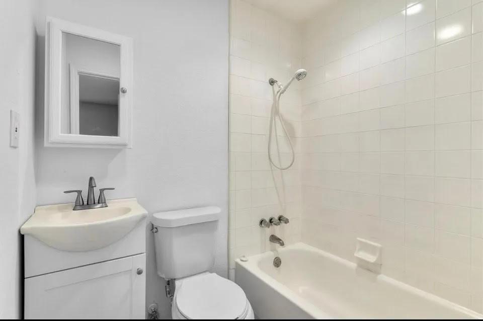 Bright bathroom showcasing an alcove tub-shower, toilet and vanity with mirror