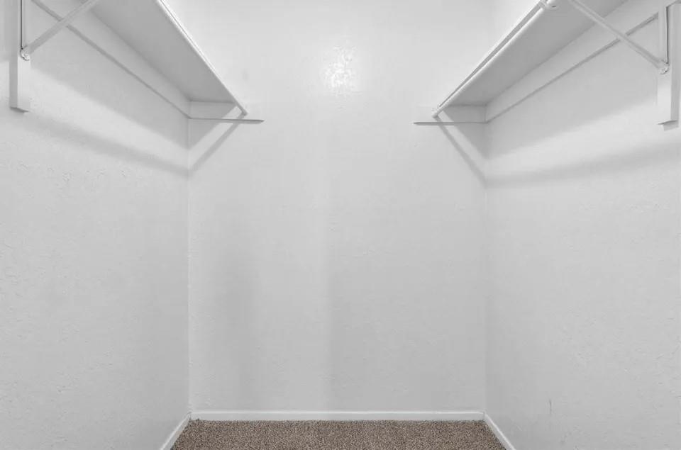 A spacious, well-kit walk-in closet featuring parallel shelves