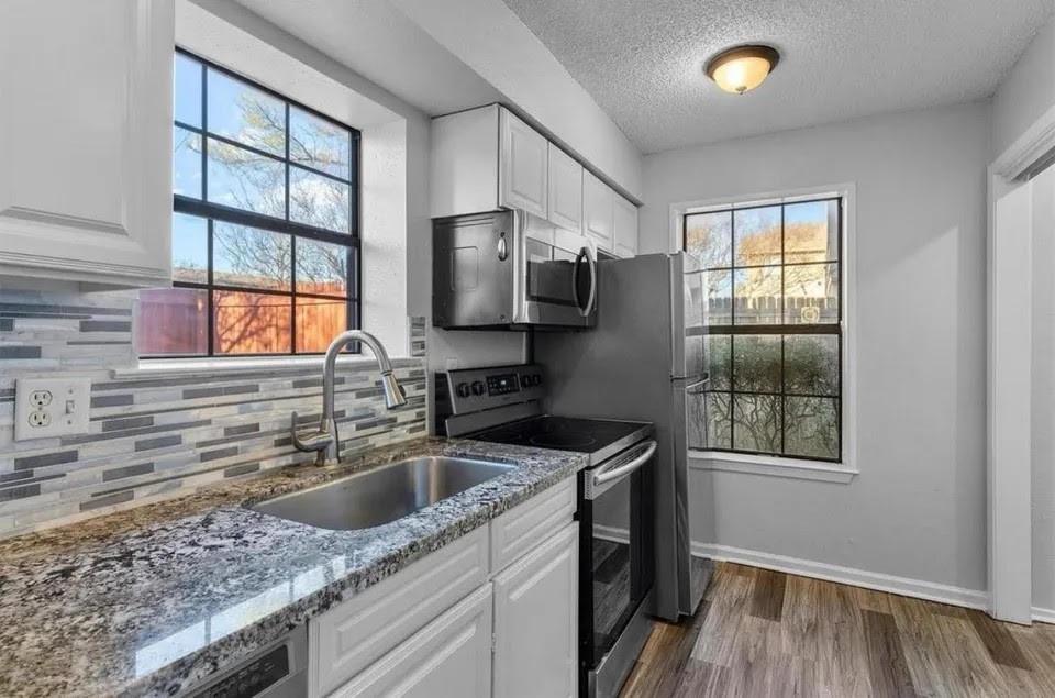 Bright kitchen showcasing stainless steel appliances, built-in cabinets and windows to let in natural light.