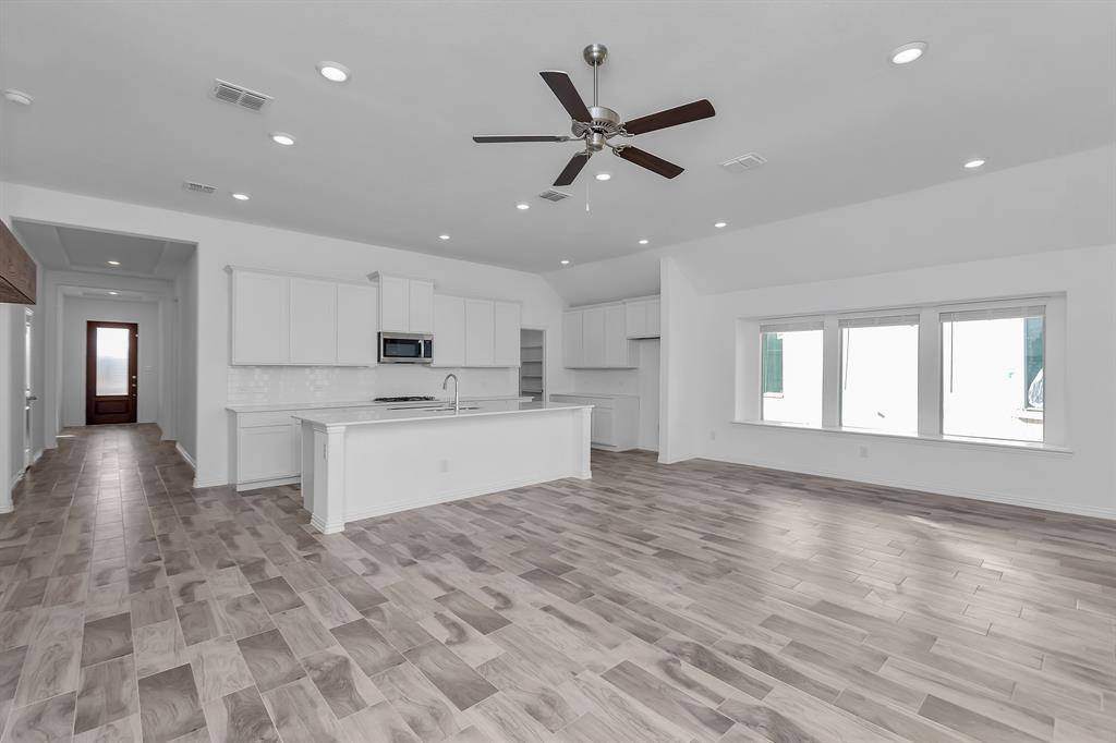 Kitchen featuring stainless steel microwave, lofted ceiling, recessed lighting, a ceiling fan, and an island with sink Kitchen featuring stainless steel microwave, lofted ceiling, recessed lighting, a ceiling fan, and an island with sink