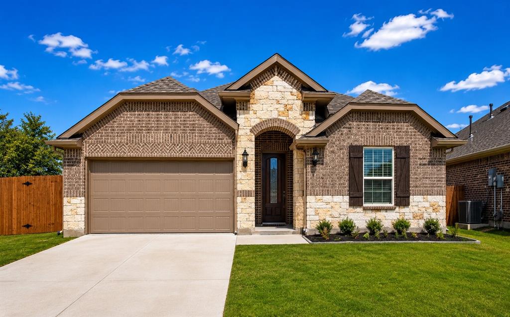 Brick and stone exterior featuring an arched entry, a two-car garage, and a manicured lawn