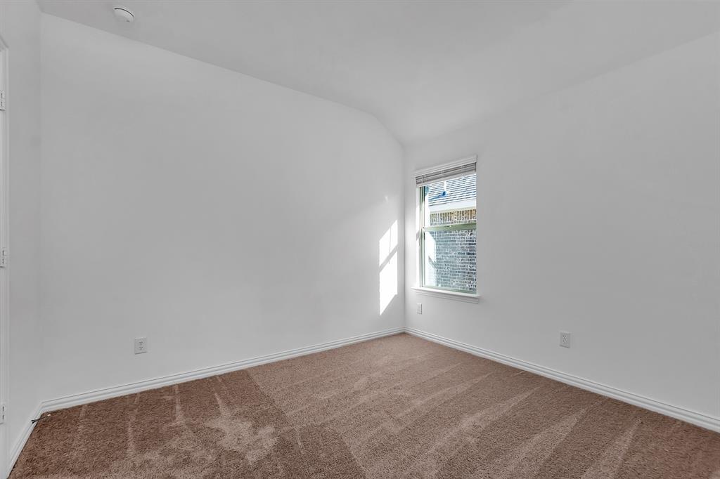 Unfurnished room featuring a smoke detector, vaulted ceiling, and carpet floors