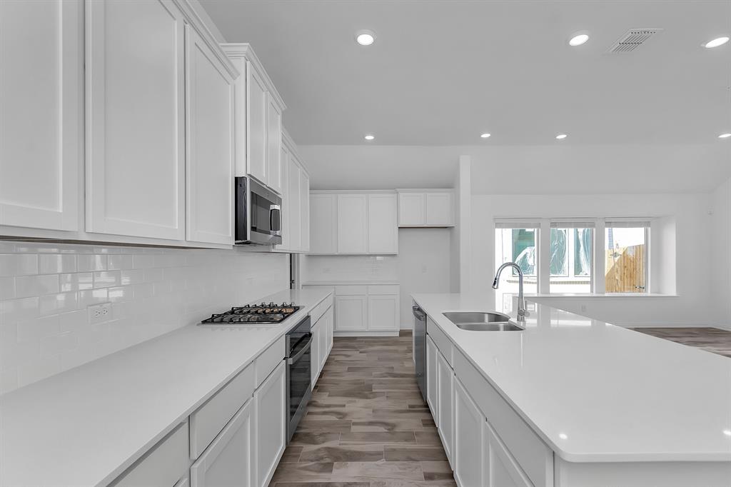Kitchen with stainless steel appliances, recessed lighting, decorative backsplash, white cabinetry, and light countertops Kitchen with stainless steel appliances, recessed lighting, decorative backsplash, white cabinetry, and light countertops