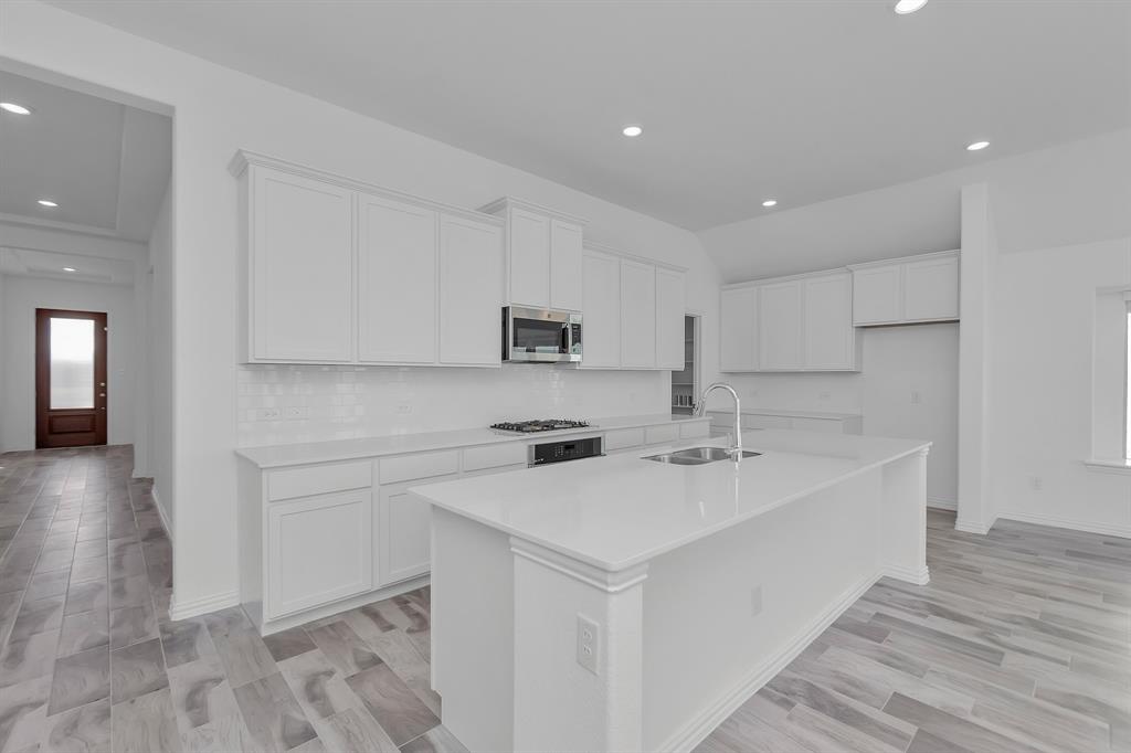 Kitchen featuring stainless steel appliances, white cabinetry, a center island with sink, tasteful backsplash, and recessed lighting Kitchen featuring stainless steel appliances, white cabinetry, a center island with sink, tasteful backsplash, and recessed lighting