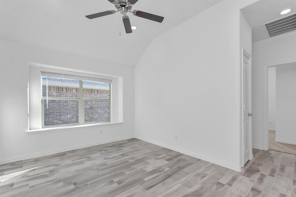 Spare room with light wood-type flooring, vaulted ceiling, and a ceiling fan