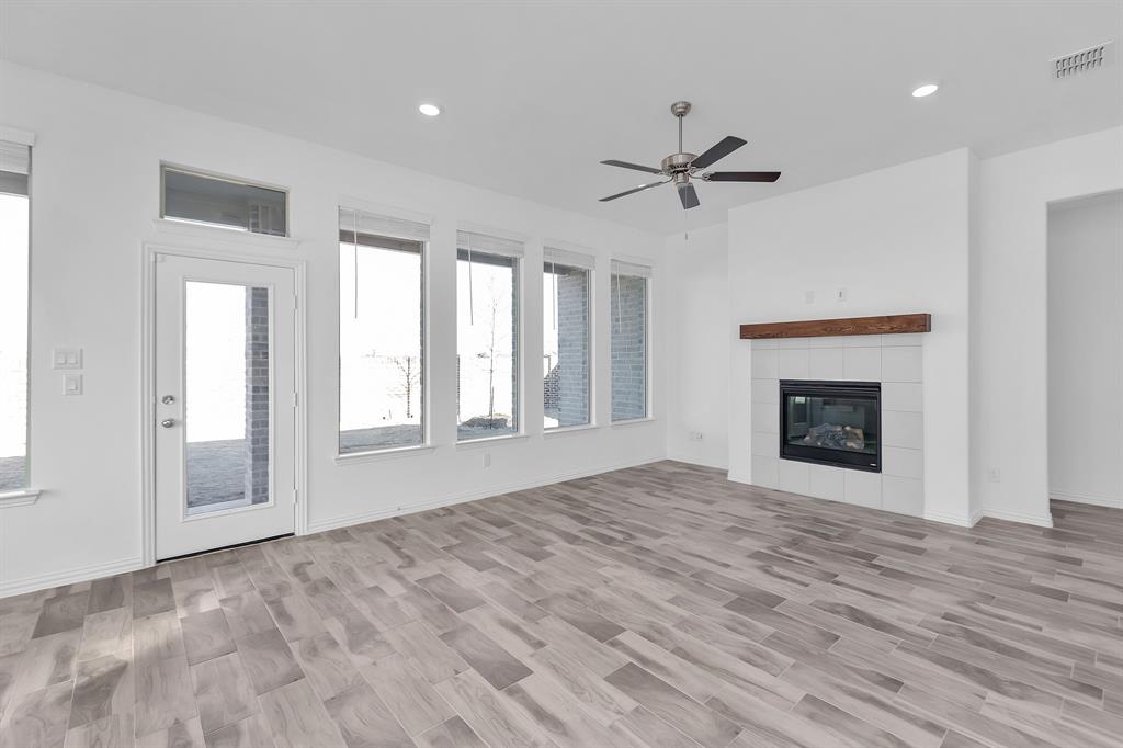 Unfurnished living room with ceiling fan, recessed lighting, a tile fireplace, and light wood-style floors Unfurnished living room with ceiling fan, recessed lighting, a tile fireplace, and light wood-style floors