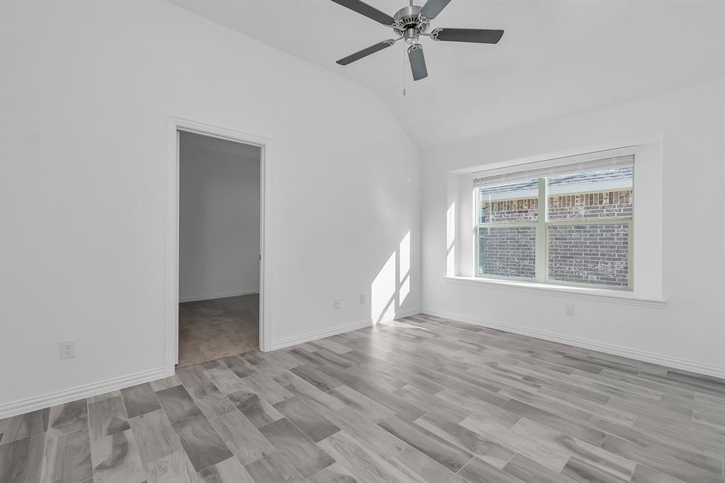 Empty room featuring vaulted ceiling and a ceiling fan