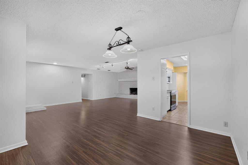 Spacious interior featuring wood-finish flooring, a white brick fireplace, and recessed lighting