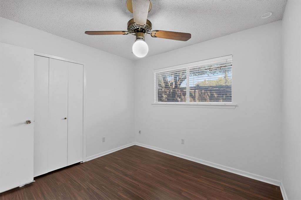 Wood-finish flooring, white walls, and a window with horizontal blinds