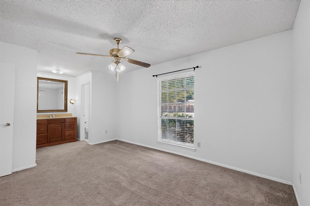 Wall-to-wall carpeting, window with blinds, ceiling fan, and an integrated vanity with a mirror