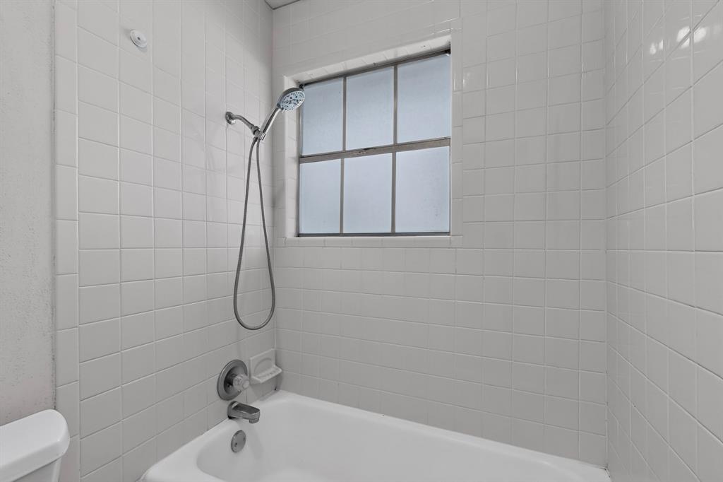 Tub and shower combination with white square tile surround, chrome fixtures, and a privacy window