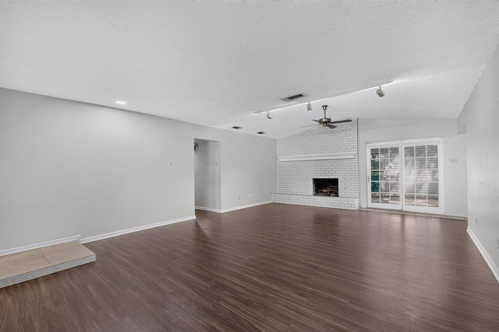 Vaulted ceiling with a ceiling fan, white brick fireplace, dark wood-finish flooring, recessed lighting, and sliding glass doors