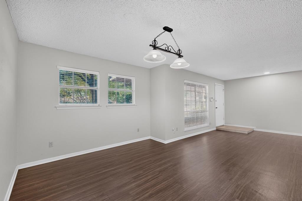Wood-finish flooring, two large windows with blinds, recessed lighting, and a front entry door with a landing