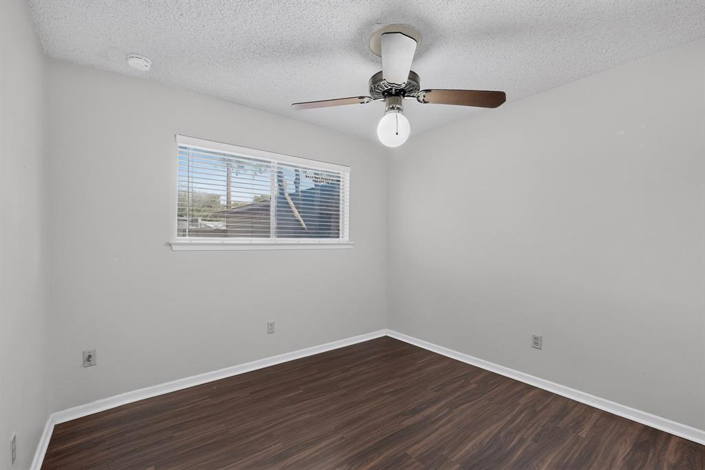 Wood-finish flooring, white baseboards, and a window with blinds