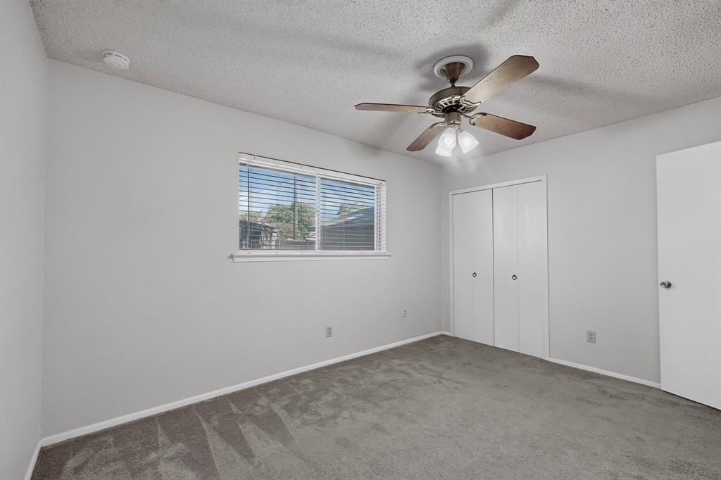 Wall-to-wall carpeting, window with blinds, ceiling fan with integrated lighting, and bi-fold closet doors