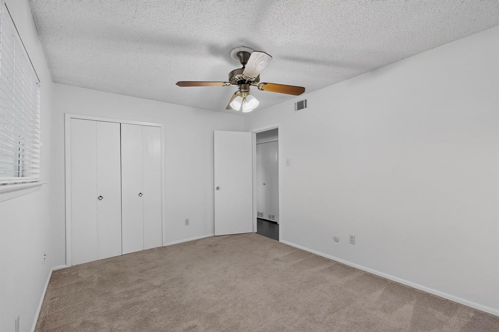 Neutral wall color, carpeted flooring, window with blinds, bi-fold closet doors, and a ceiling fan with integrated lighting