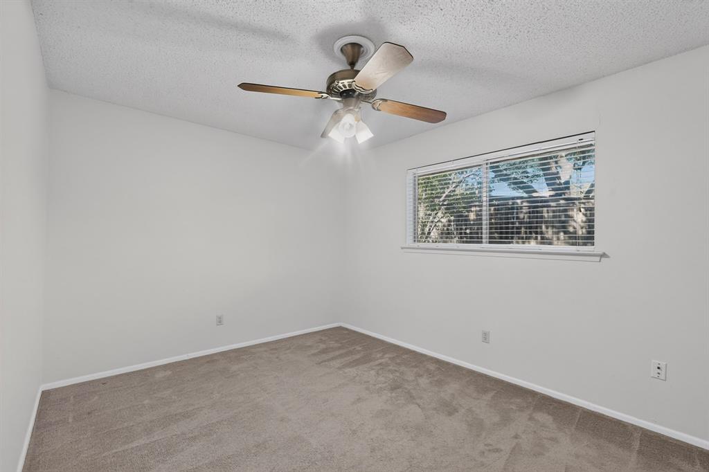Recessed window with horizontal blinds, overhead ceiling fan with light fixture, textured ceiling, and carpeting