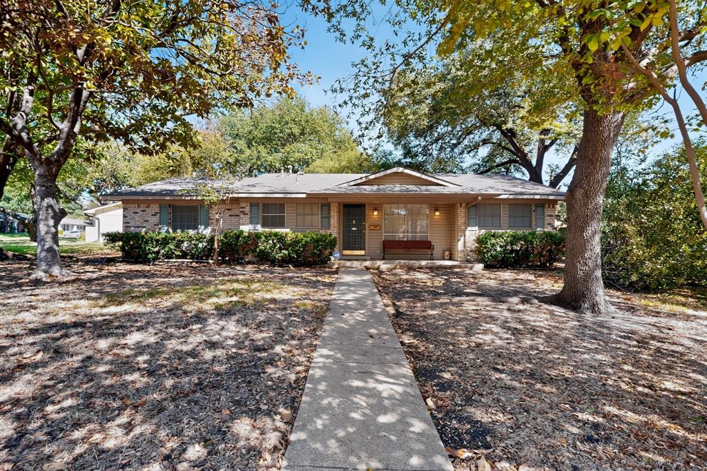 Brick and siding exterior with a front walkway, mature trees, and established landscaping