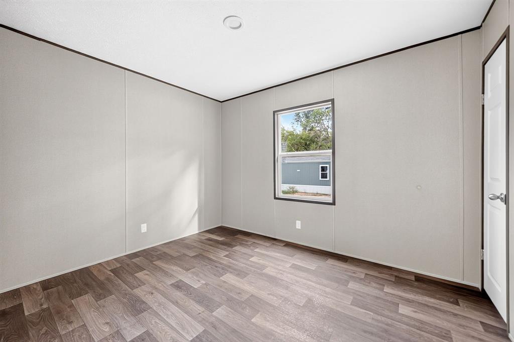 Neutral wall panels with dark trim, wood-finish flooring, and a single-pane window