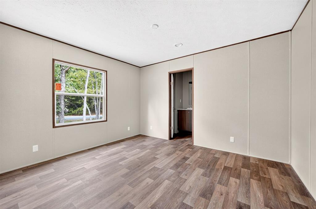 Neutral-toned wall paneling, wood-finish flooring, and a single-pane window with dark trim
