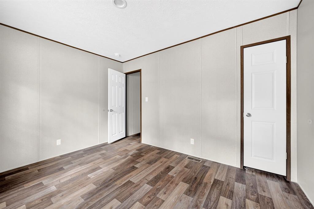 Interior room featuring wood-finish flooring, neutral panel walls, recessed ceiling lighting, and six-panel interior doors with dark wood-tone frames