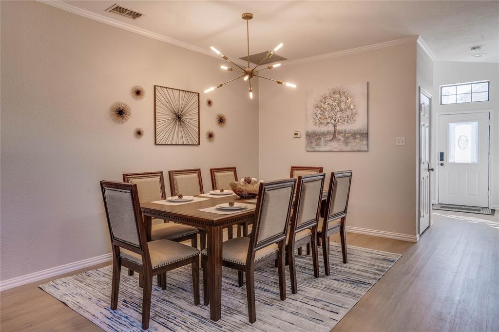 Dining area with a modern linear chandelier, crown molding, and wood-finish flooring