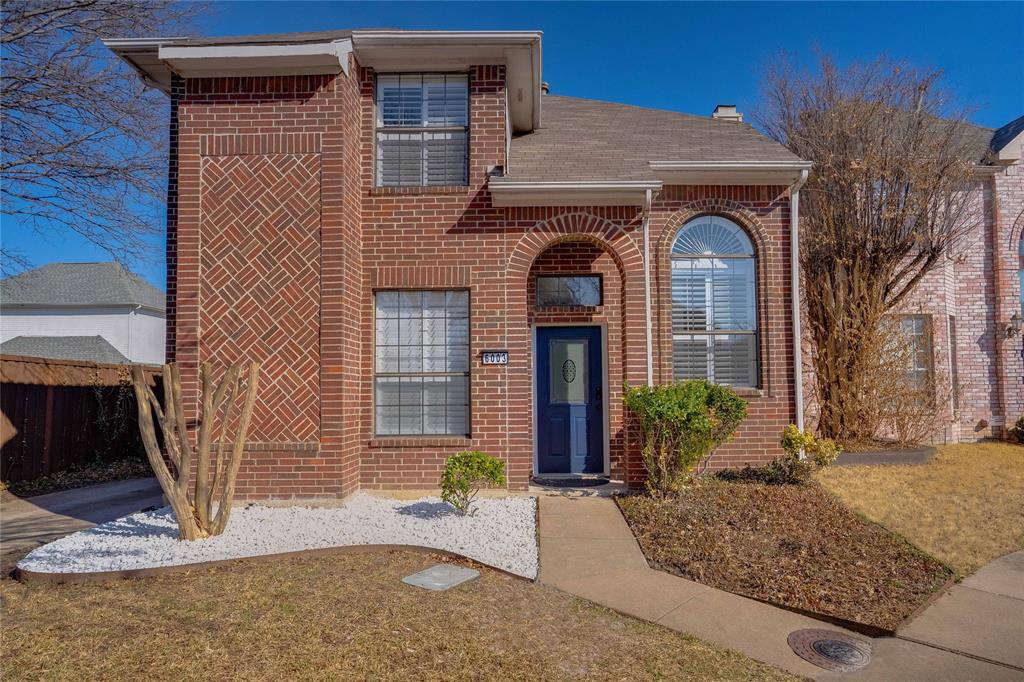 Brick exterior featuring decorative herringbone pattern, arched entryway, dark blue door, and an arched window