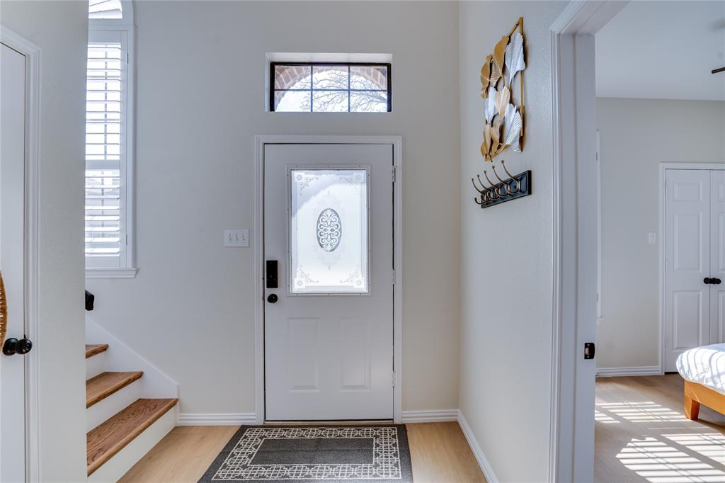 Entryway featuring a decorative frosted glass front door with transom window, wood-finish flooring, and natural light