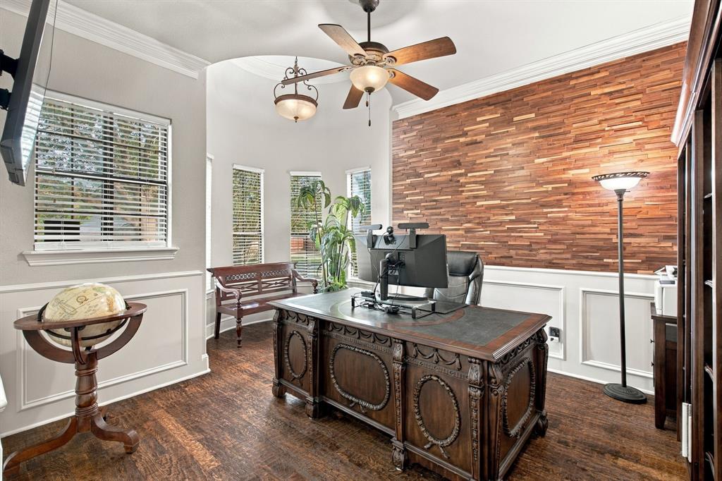 Room featuring a textured wood-slat accent wall, extensive wall paneling, wood-finish flooring, a vaulted ceiling with a multi-light chandelier and ceiling fan, and a curved window bank