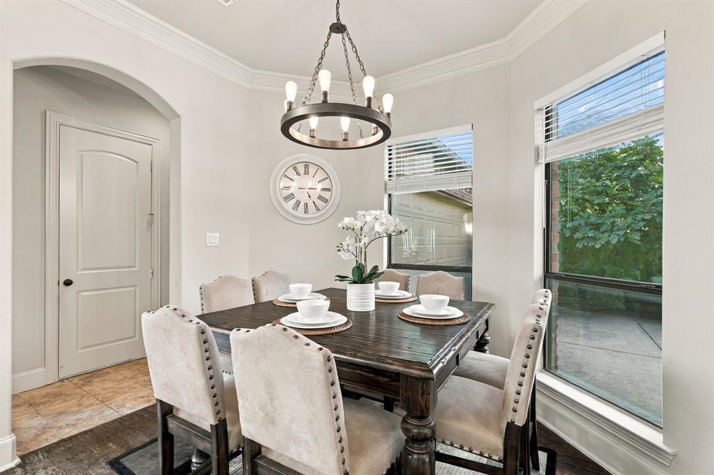 Dining area featuring crown molding, arched entryway, large windows with horizontal blinds, wood-finish flooring, and a circular metal chandelier
