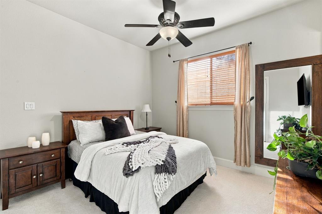 Bedroom featuring high ceilings, neutral wall tones, wall-to-wall carpeting, a multi-blade ceiling fan with integrated lighting, and a single window with horizontal blinds
