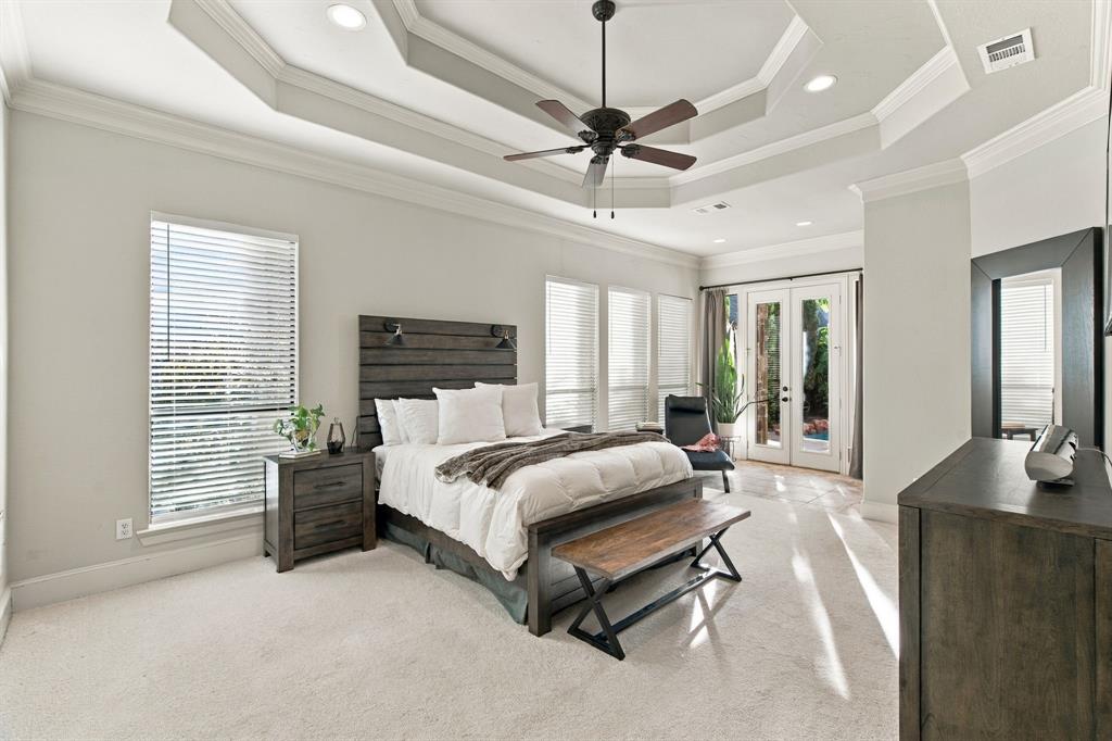 Tray ceiling with recessed lighting, central ceiling fan, neutral carpeting, multiple windows with blinds, and glass-paned doors