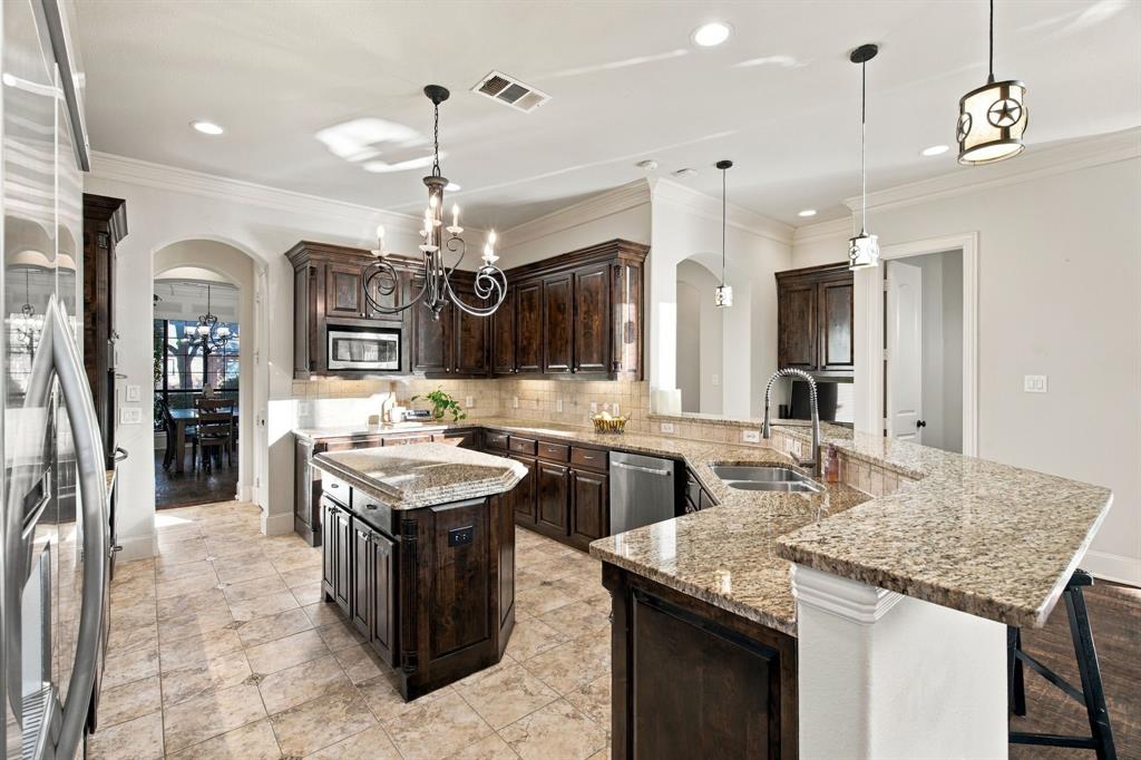 Kitchen featuring dark stained cabinetry, stone countertops, central island, tiled flooring, and arched doorways